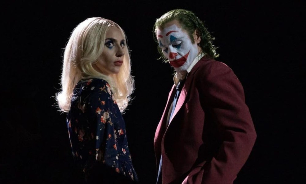 Lady Gaga as Harley Quinn and Joquin Phoenix as Joker pose next to each other.