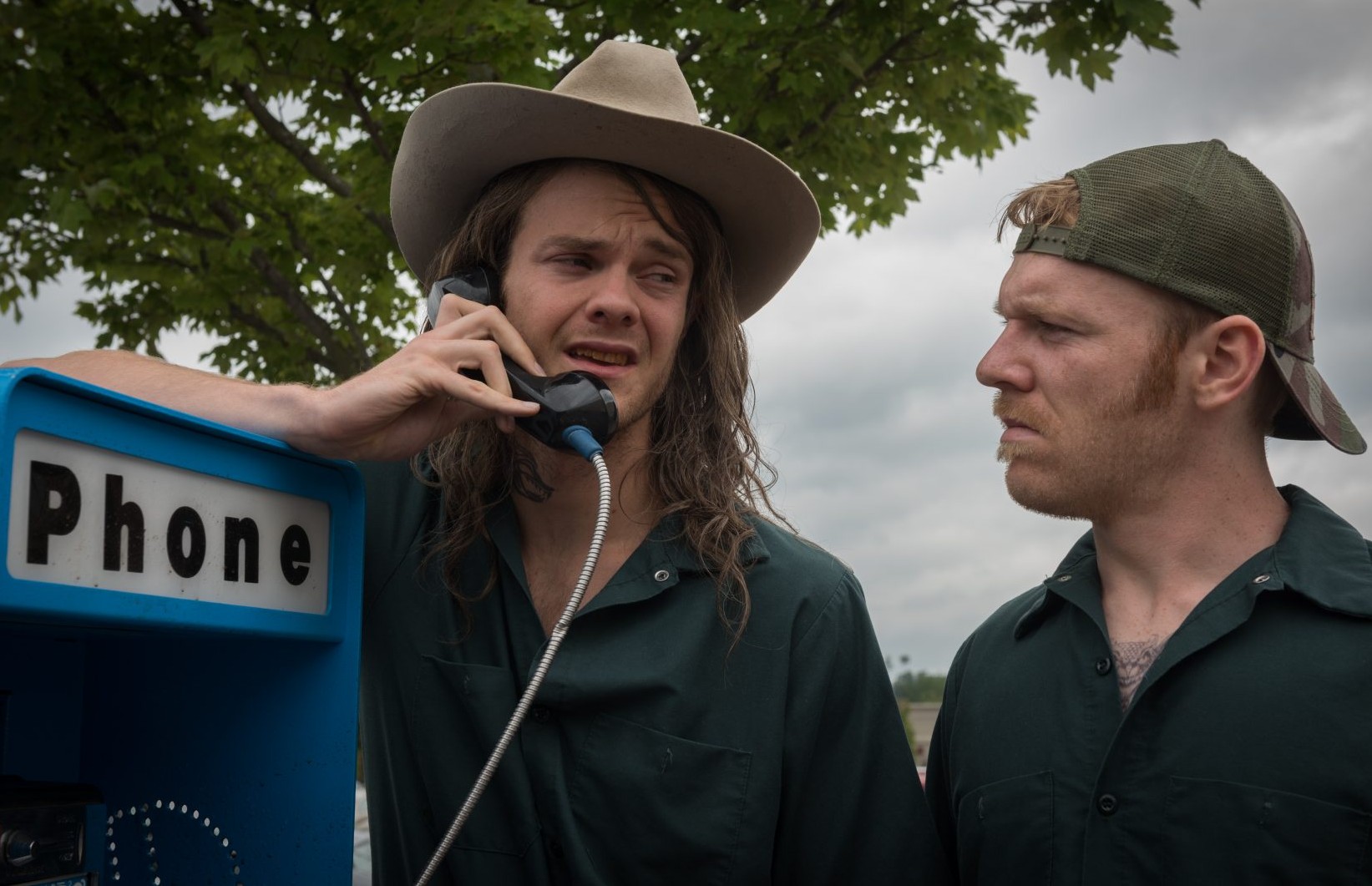 Two men talk on a pay phone in Logan Lucky.