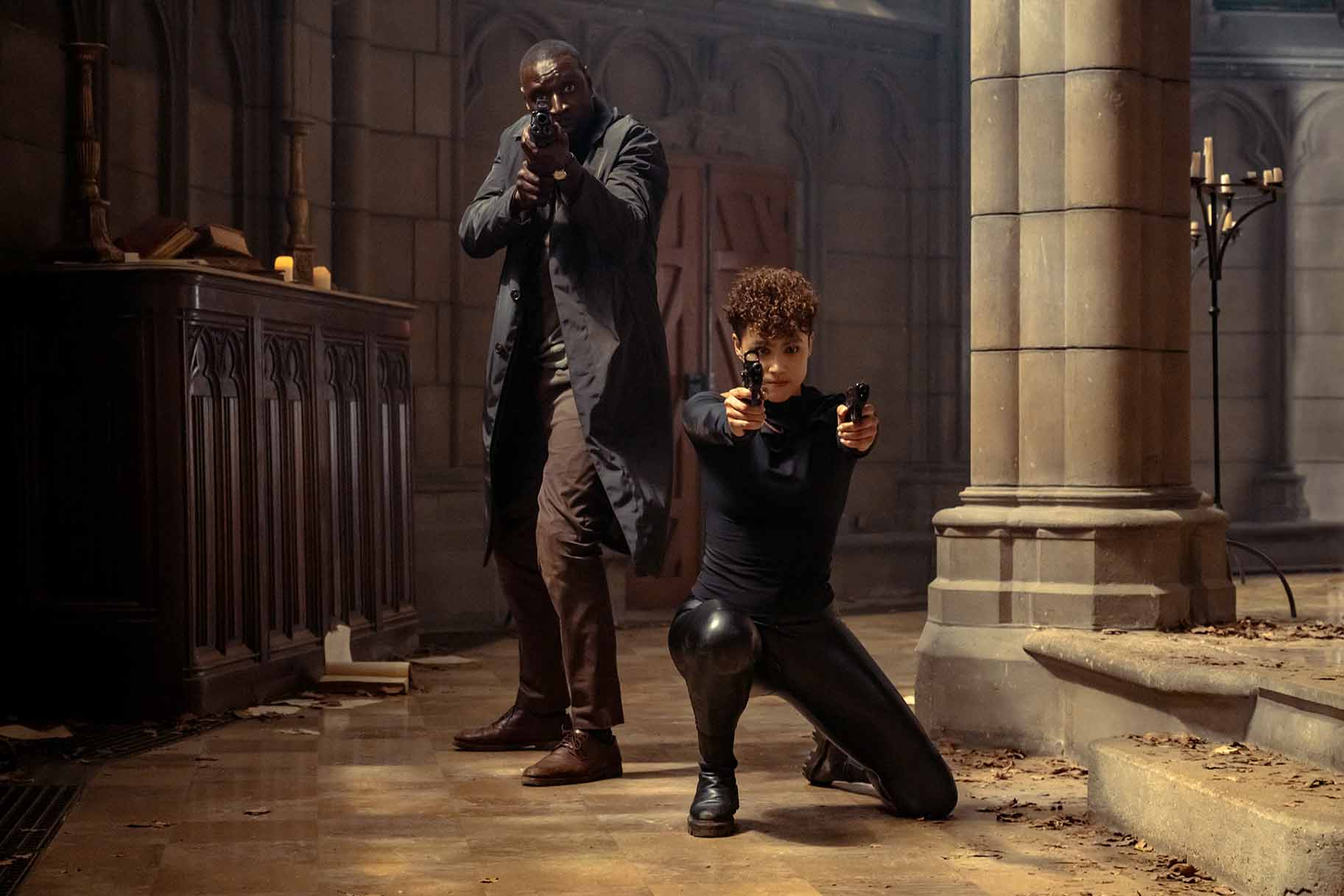 Omar Sy y Nathalie Emmanuel posan con armas en una iglesia en The Killer.