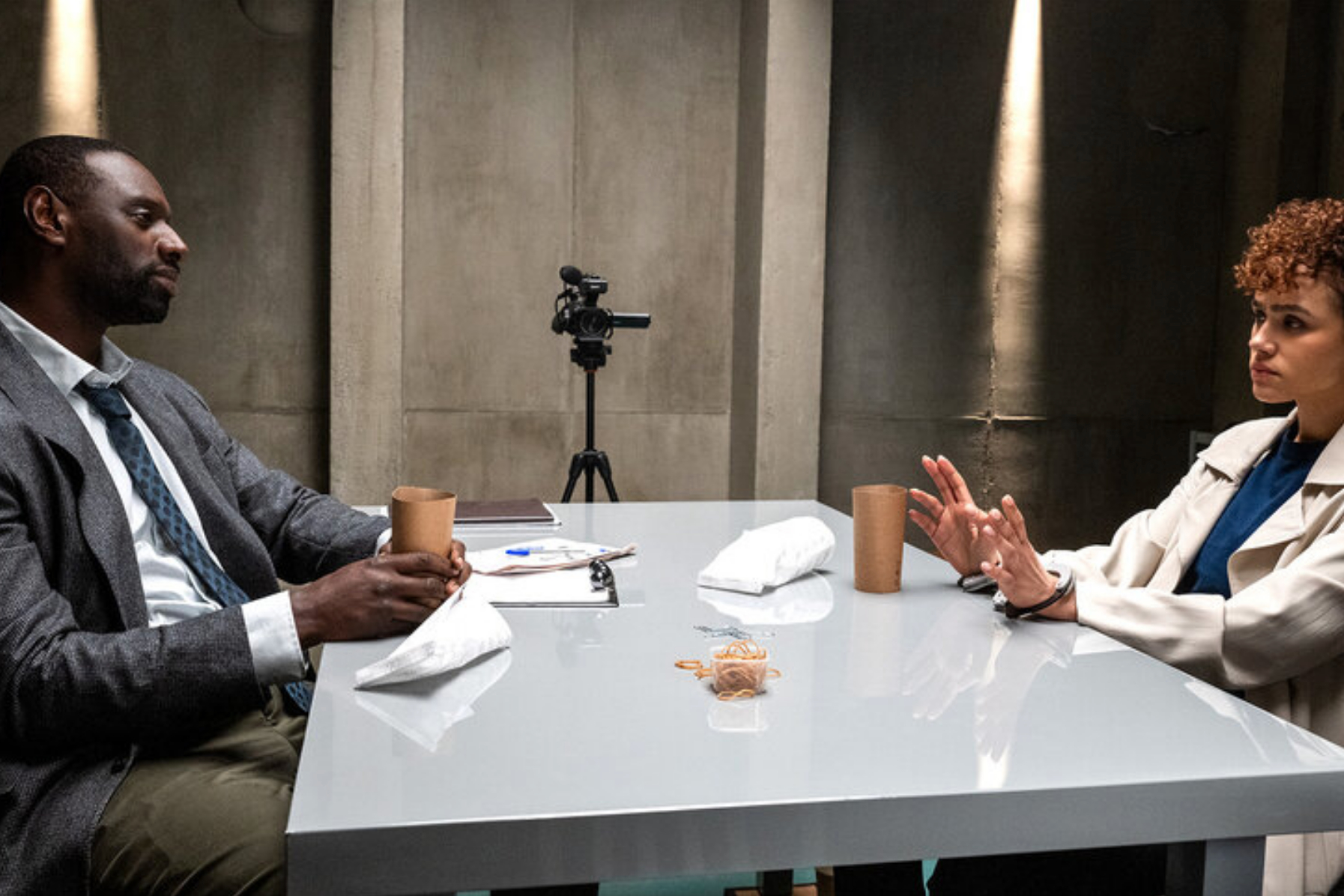 Omar Sy y Nathalie Emmanuel se sientan uno frente al otro en una mesa en The Killer.