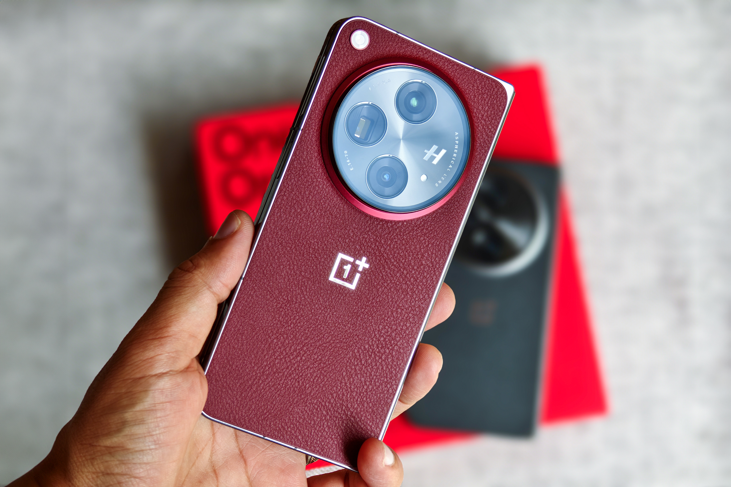 OnePlus Open Apex Edition Crimson Shadow red held in hand in front of the black variant.