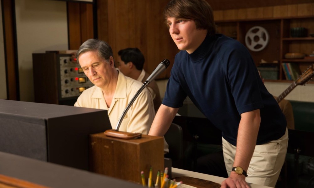 Paul Dano stands in front of a control panel with a microphone.