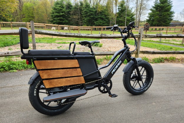 Pedego Cargo right profile parked on asphalt on a farm with fences, barns, and livestock.