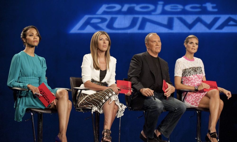 Four judges sit in chairs as the look at a runway.