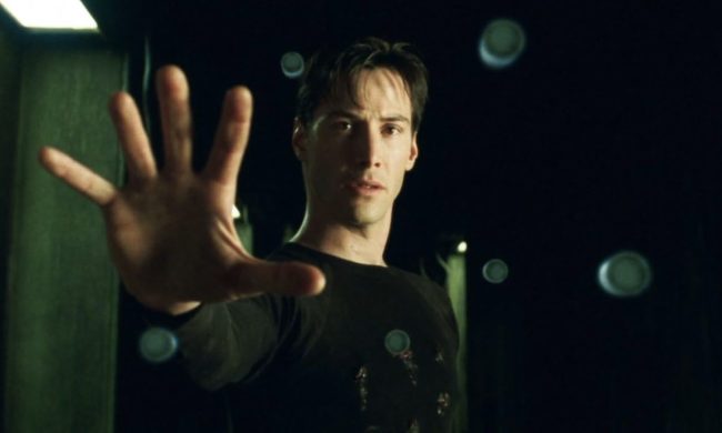 Keanu Reeves puts his hands up and stares in The Matrix.