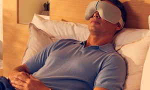 A man using the Therabody Smart Goggles while lying on a bed.