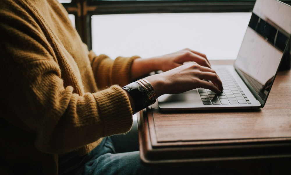 A side view of a person typing on a laptop.