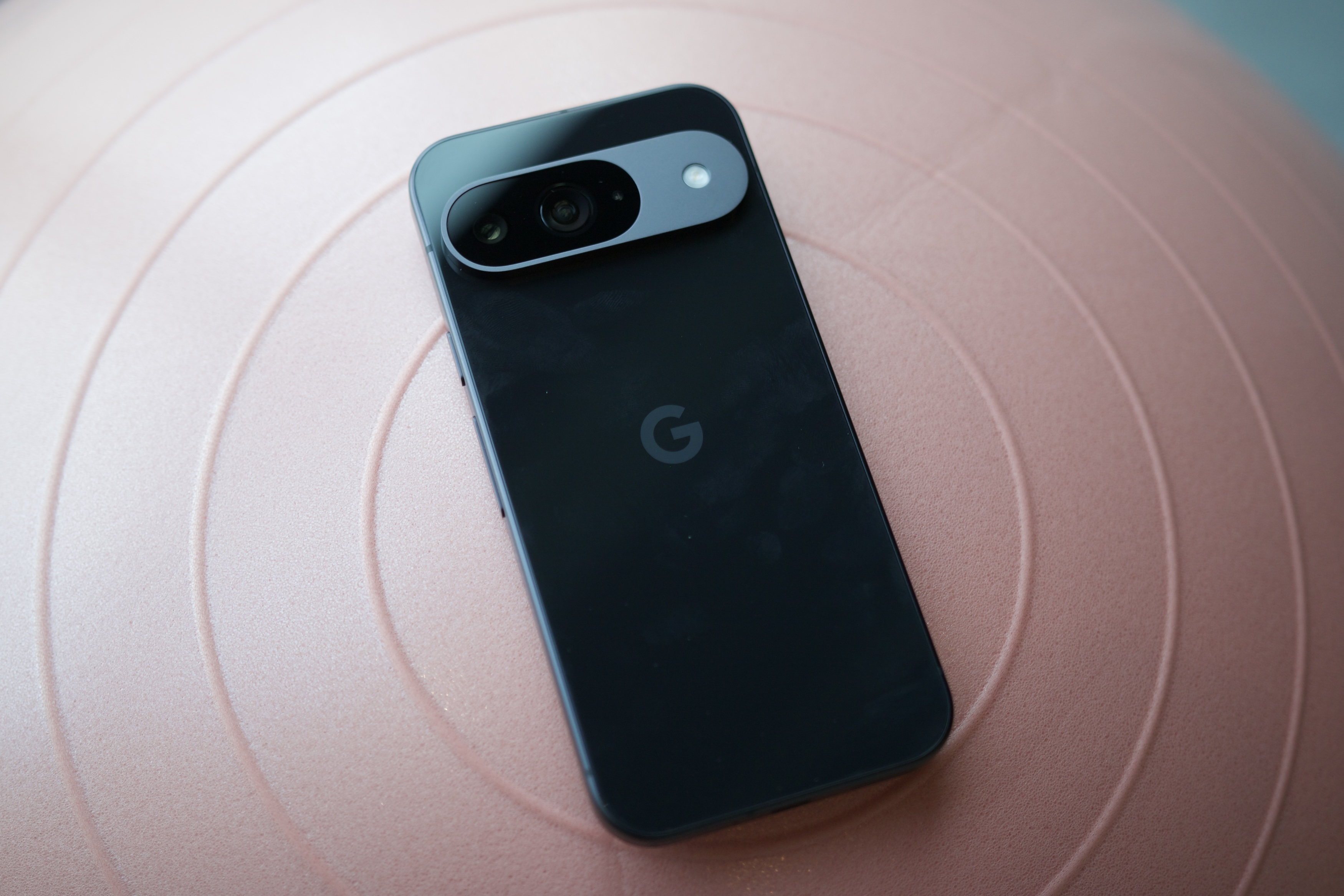 Un Google Pixel 9 negro boca abajo sobre una pelota de ejercicio.