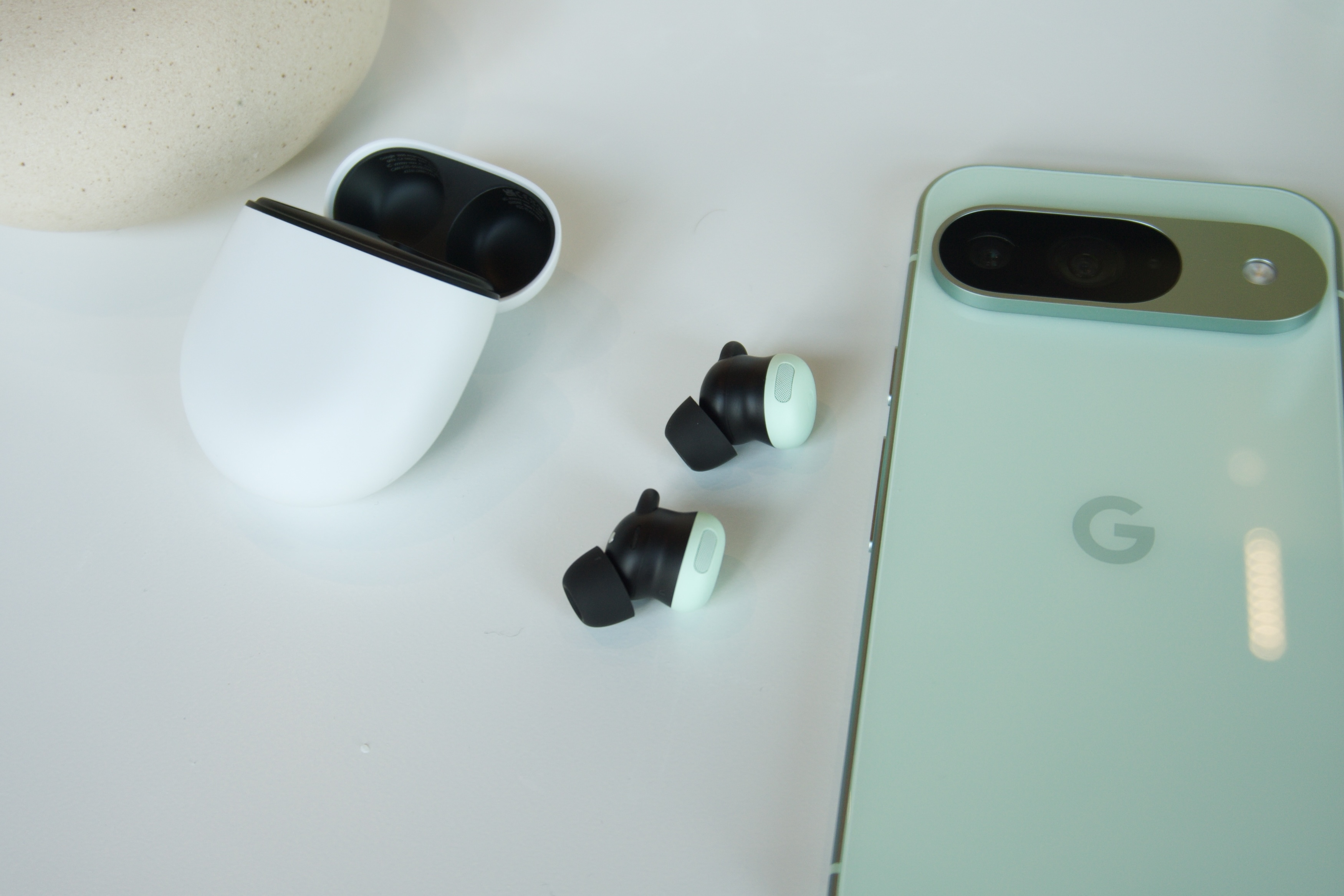 充电盒旁边的 Google Pixel Buds Pro 2 和 Pixel 9。