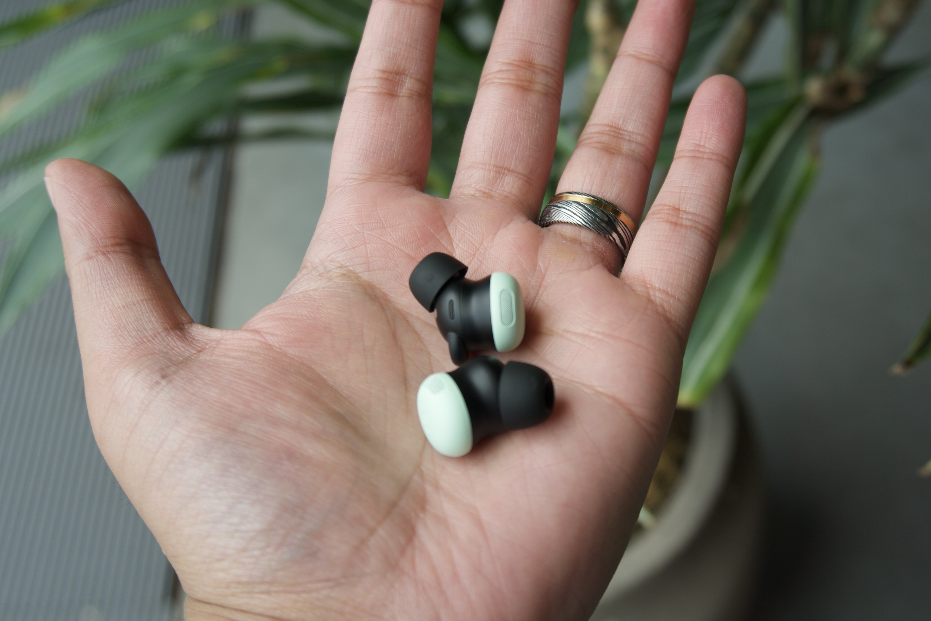 Someone holding a pair of Google Pixel Buds Pro 2.