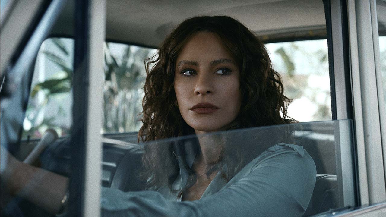 Sofia Vergara como Griselda na série de mesmo nome, sentada no banco do motorista de um carro com a janela aberta parecendo irritada.