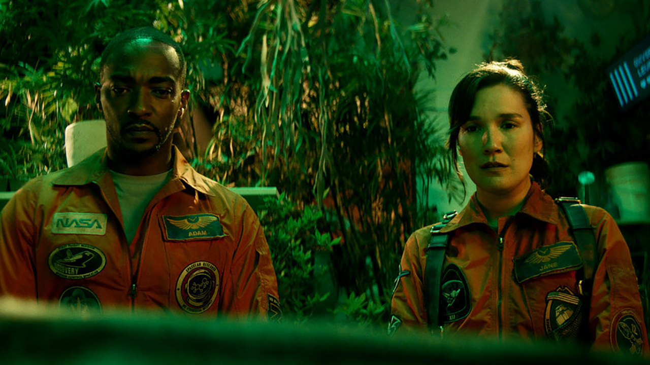 Anthony Mackie und Zoe Chao tragen Astronautenuniformen und stehen in „If You Were the Last on Peacock“ an einem Fenster mit grünem Hintergrund.