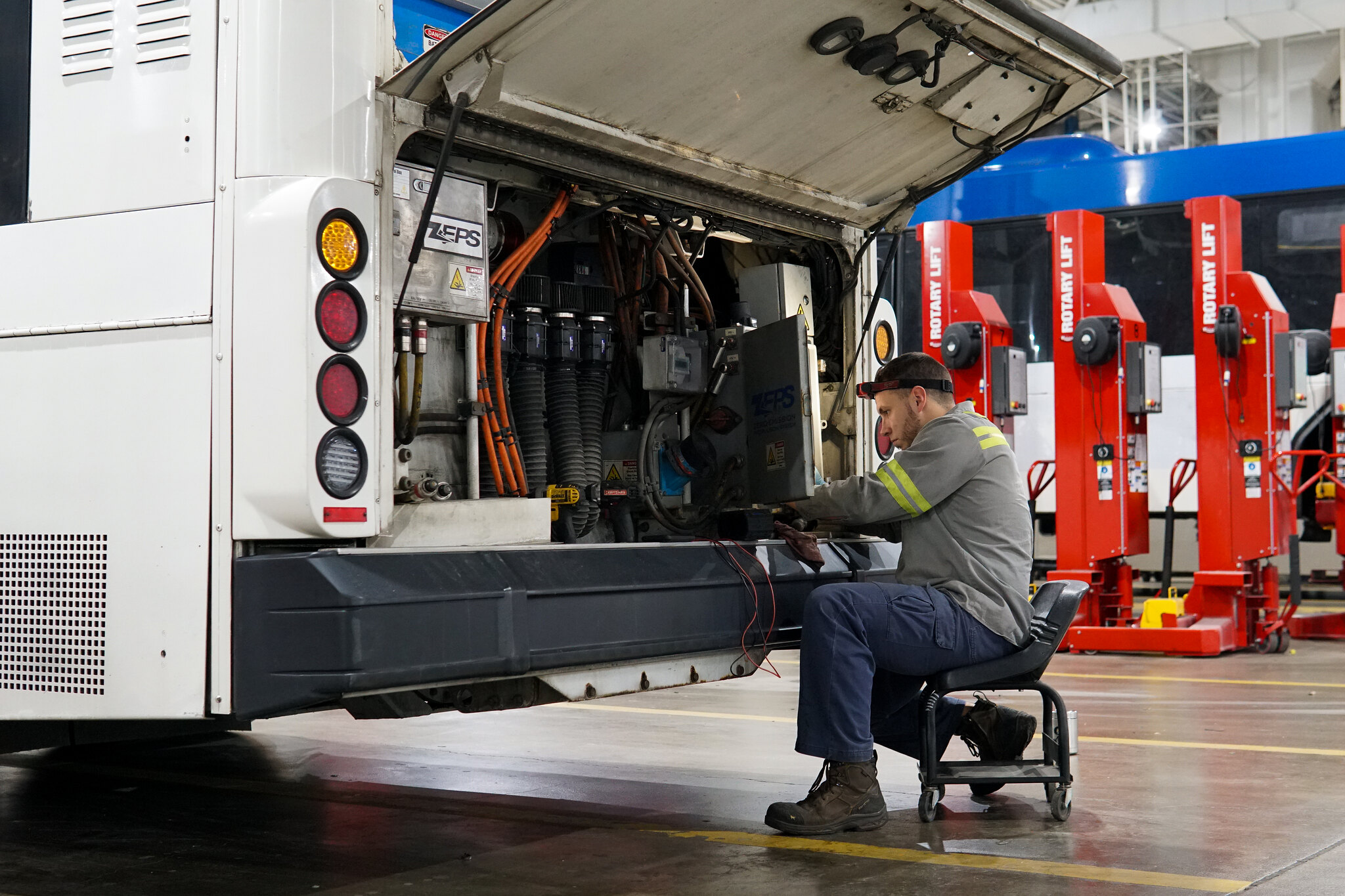 Um homem consertando um ônibus elétrico. 