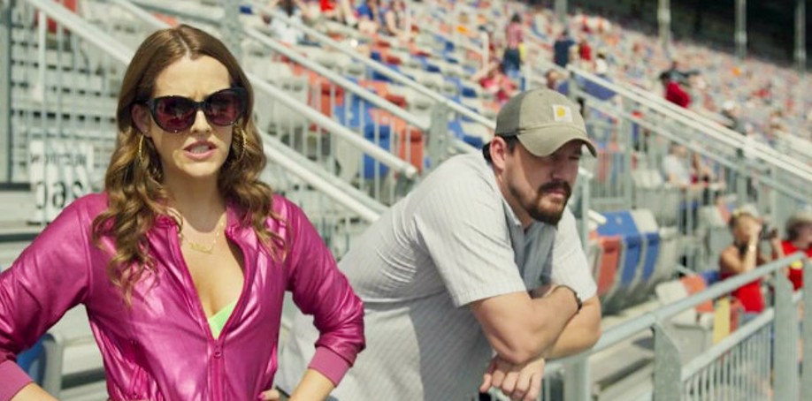 Um homem e uma mulher assistem a uma corrida de carros em Logan Lucky.