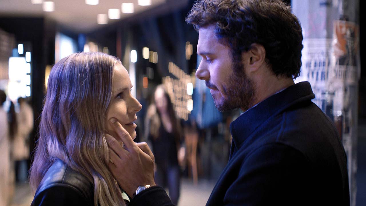 A man holds his hand to a woman's cheek as they stare at one another, a blurred scene of people in the background on Nobody Wants This.