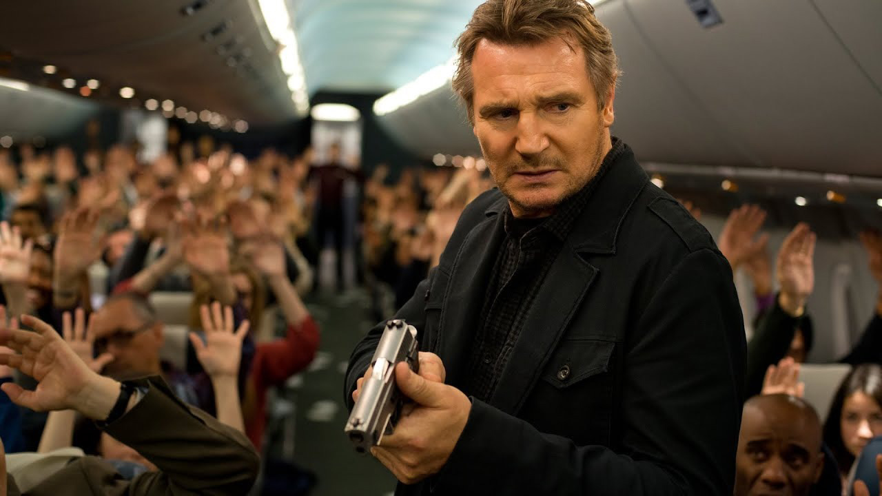 Liam Neeson sosteniendo una pistola en un avión lleno de pasajeros con las manos en alto en Non-Stop.