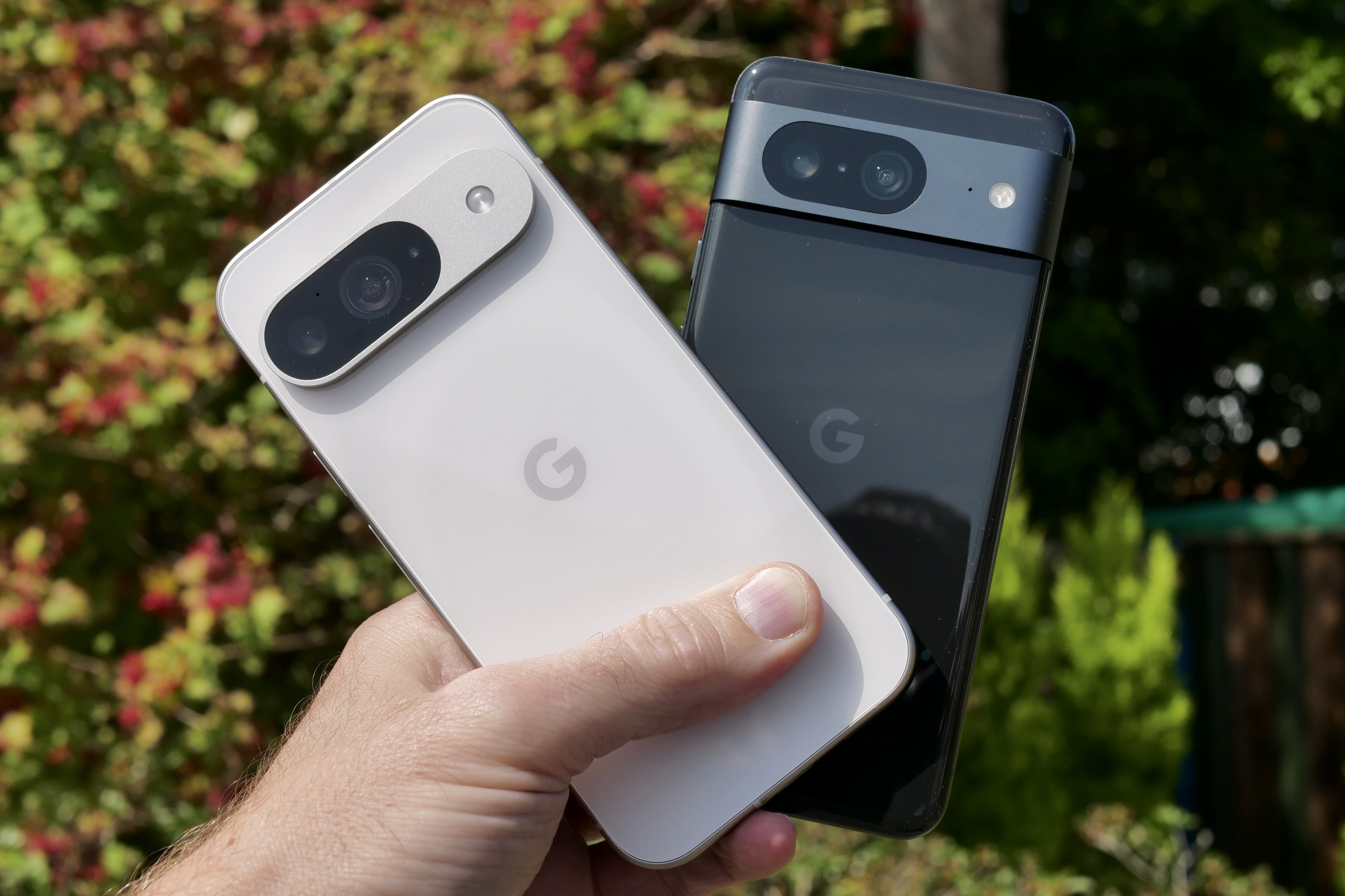 Uma pessoa segurando o Google Pixel 9 e o Google Pixel 8.