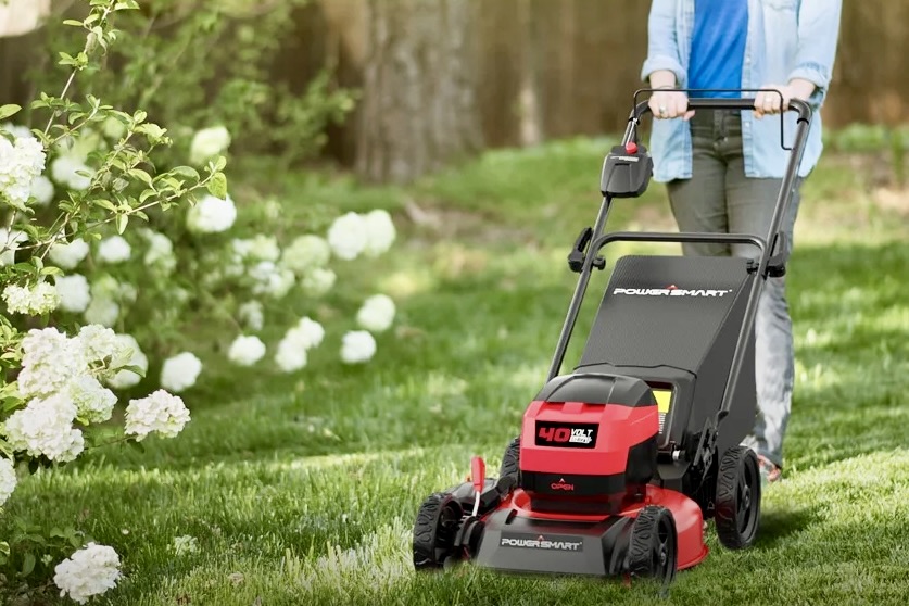 Une personne utilisant la tondeuse poussée à batterie PowerSmart 40 V dans un jardin.