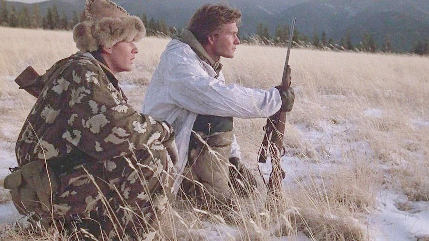 Two men sit in a field in Red Dawn.