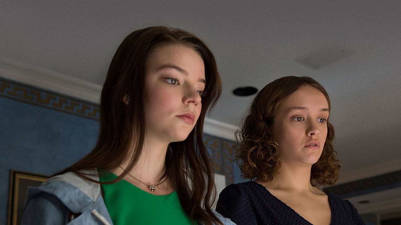 Two young women looking down at something in a scene from Thoroughbreds.