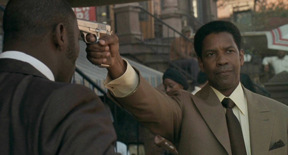 Un homme pointe une arme sur la tête d'un autre homme dans American Gangster.