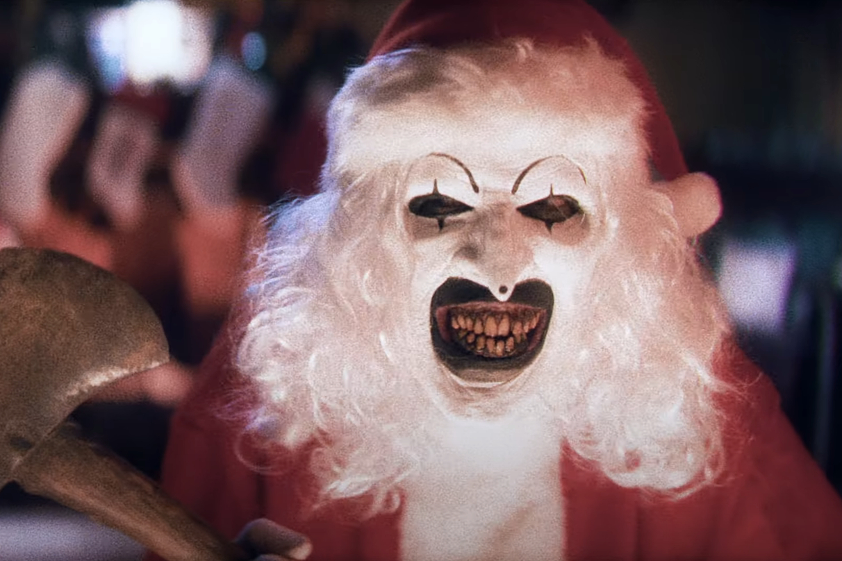 Art the Clown holds an axe while wearing a Santa costume in Terrifier 3.