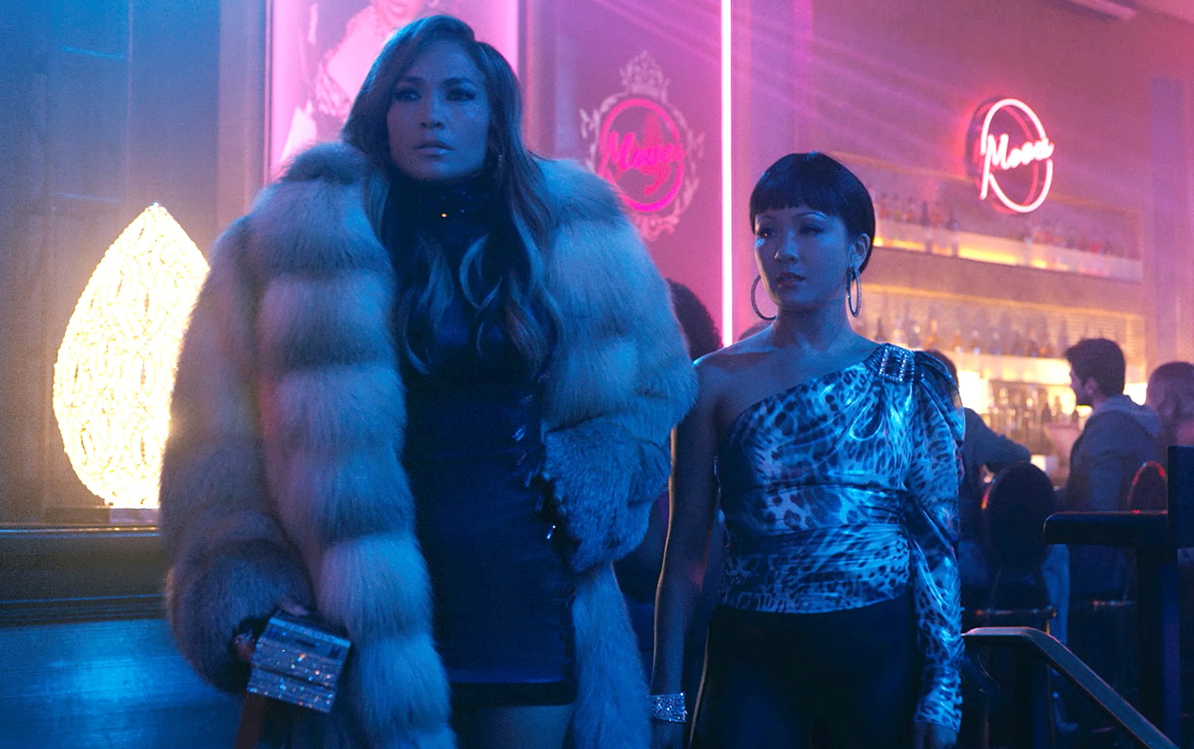 Two women stand in a club in Hustlers.