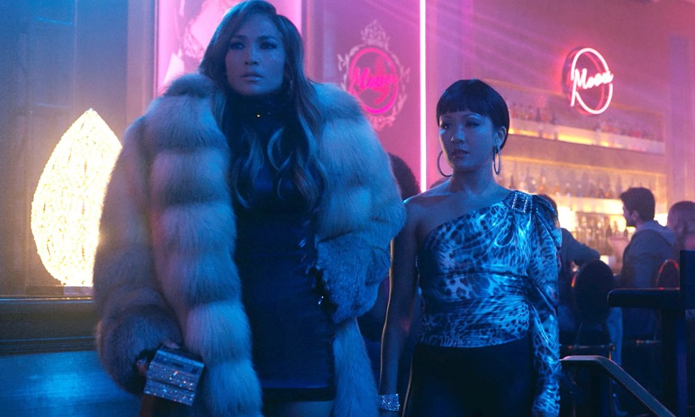 Two women stand in a club in Hustlers.