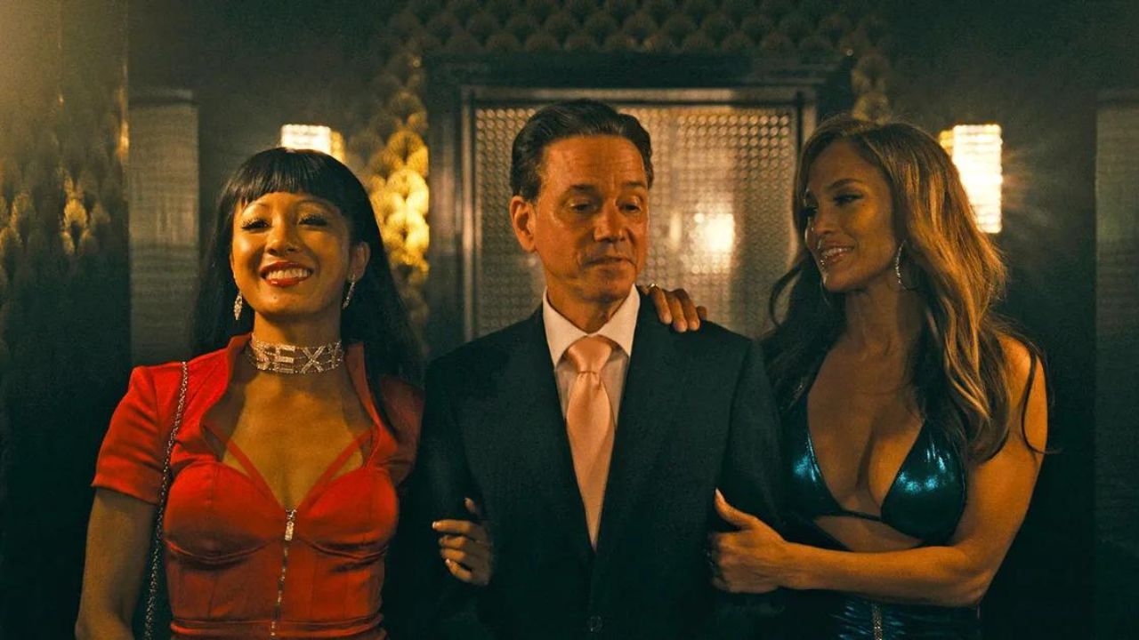 Constance Wu and Jennifer Lopez as Destiny and Ramona walking with a businessman in Hustlers.