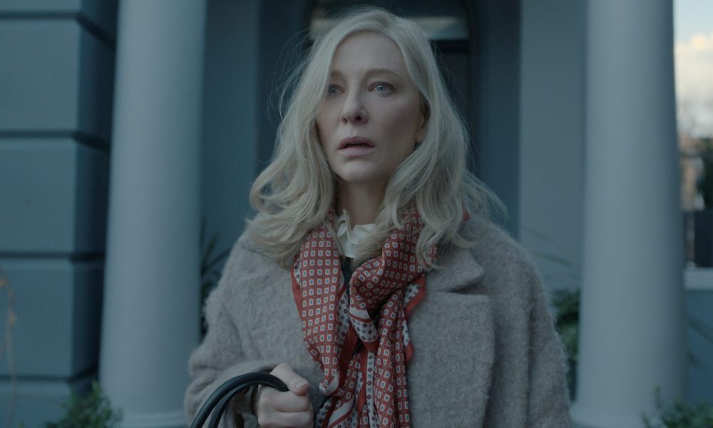 Cate Blanchett looks scared as she stands outside a front door.