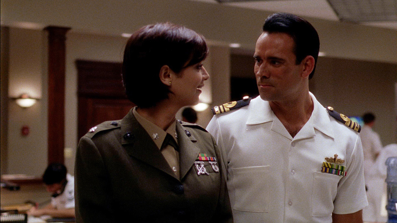 A woman and man in Navy uniforms looking at one another smiling on JAG.