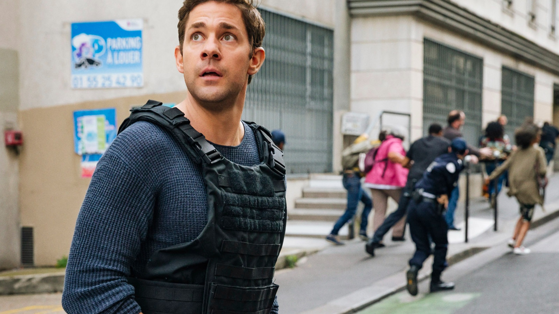 John Krasinski como Jack Ryan vestindo um colete na adaptação do Prime Video.