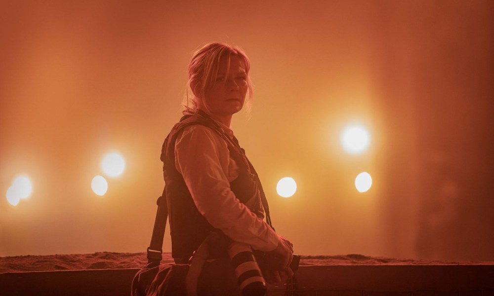 Kirsten Dunst stands near bright lights in Civil War.