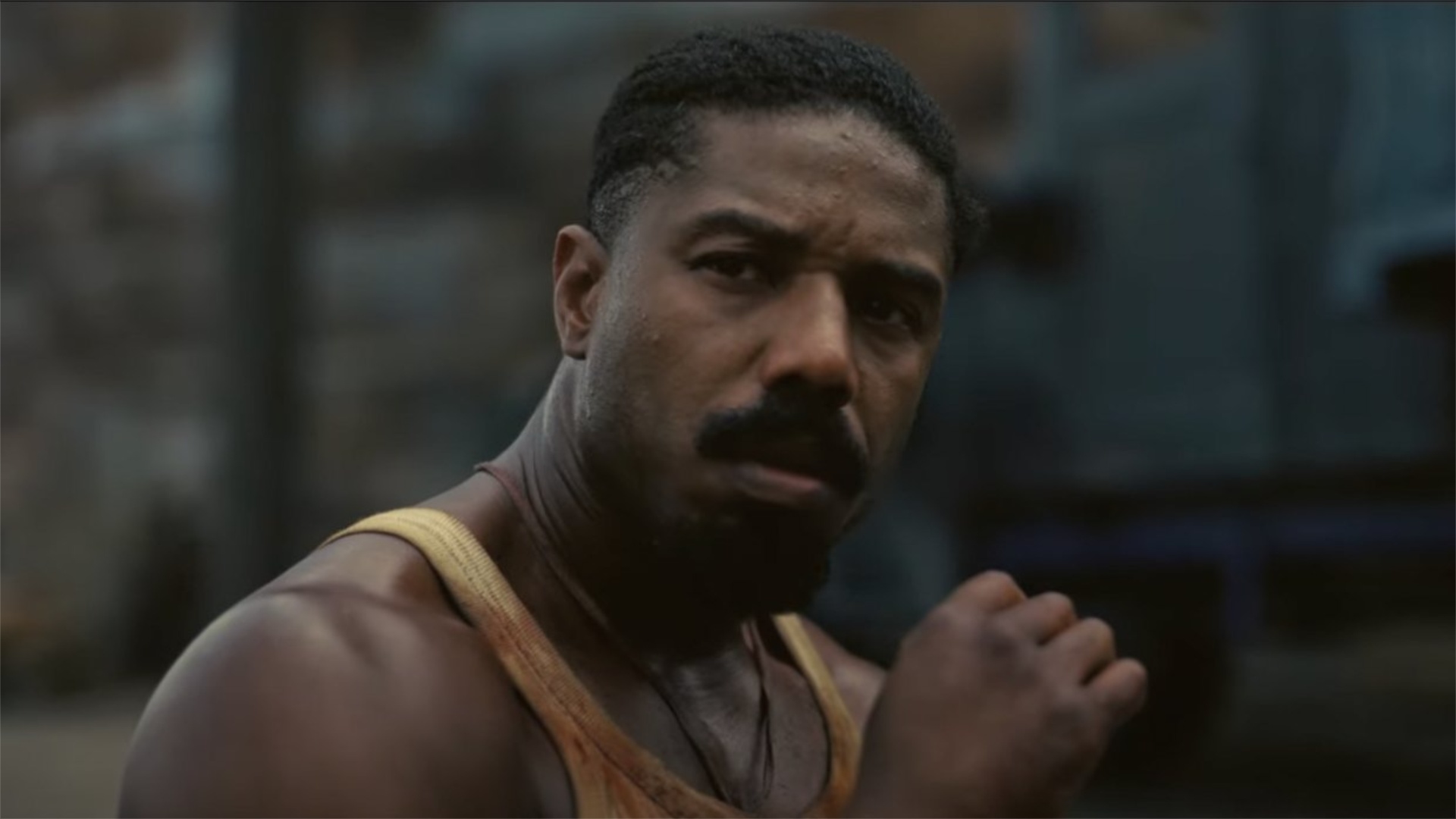 Michael B. Jordan olha com o punho fechado.