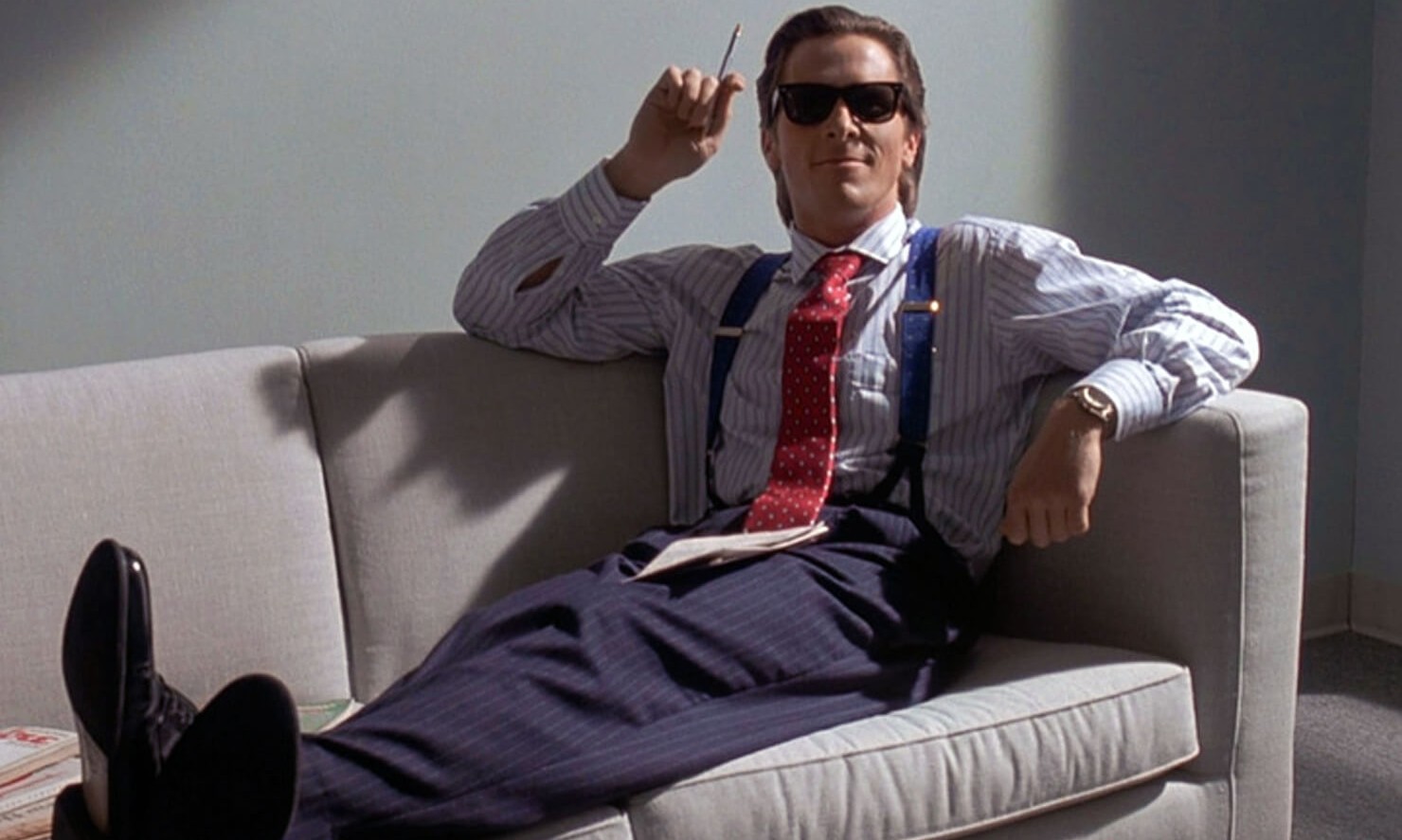 In „American Psycho“ sitzt ein Mann auf einer Couch.