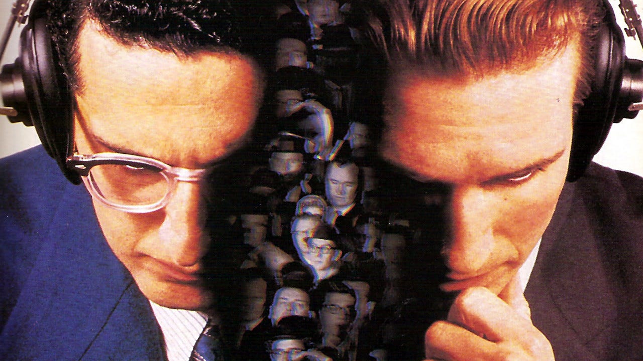 A blended image for the movie Quiz Show showing John Turturro and Ralph Fiennes wearing headphones with their faces looking down. In the space between them is a crowd of people.