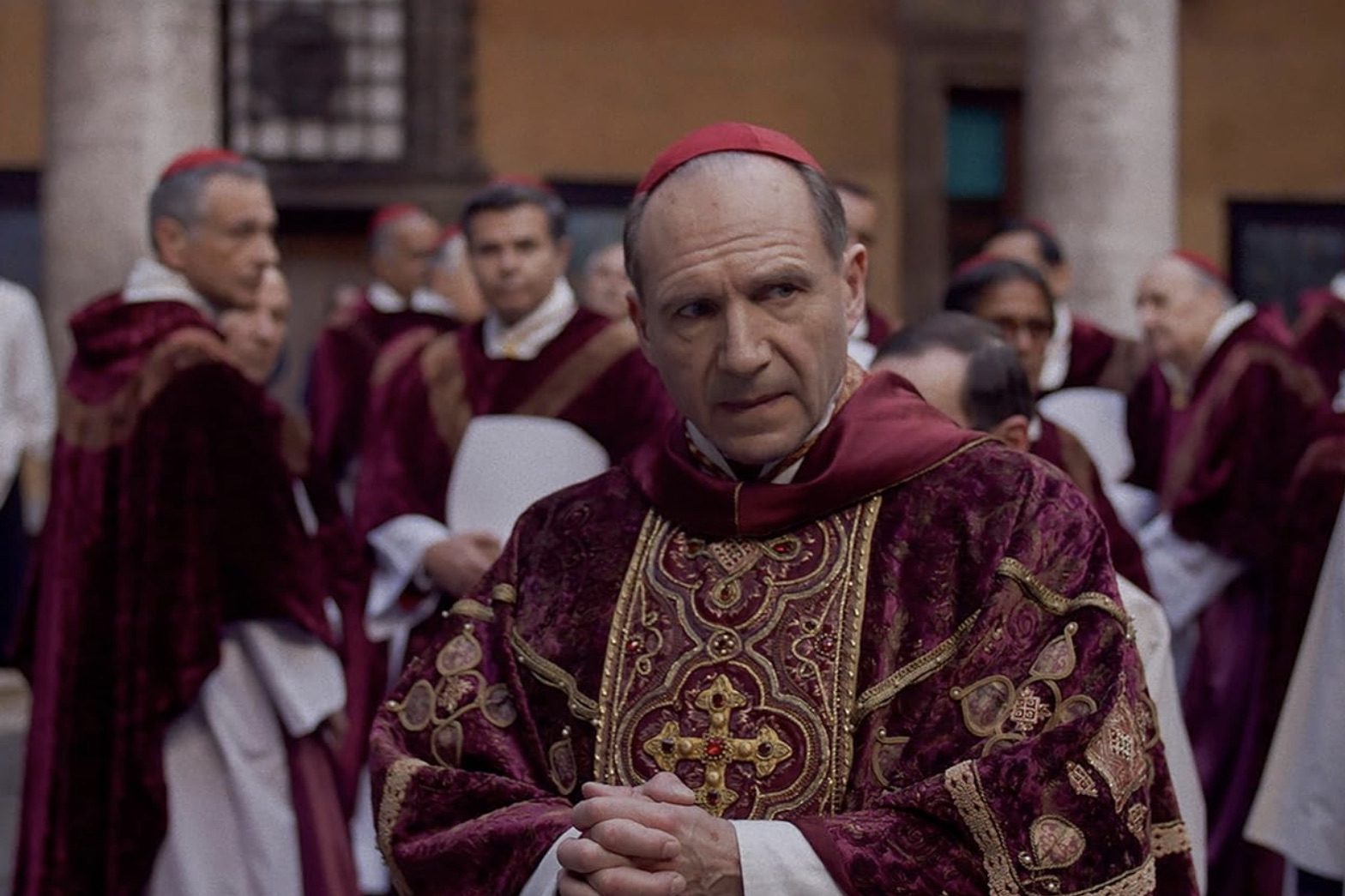 Ralph Fiennes dressed as a pope looks to his left.