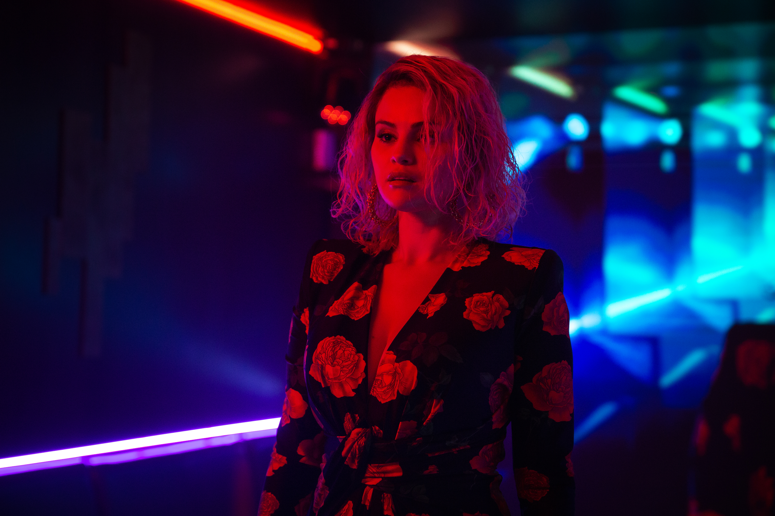 Selena Gomez stands in a hallway with neon light in a still from the movie Emilia Pérez.