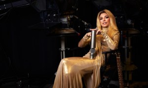 Shania Twain sits down and poses with an award.