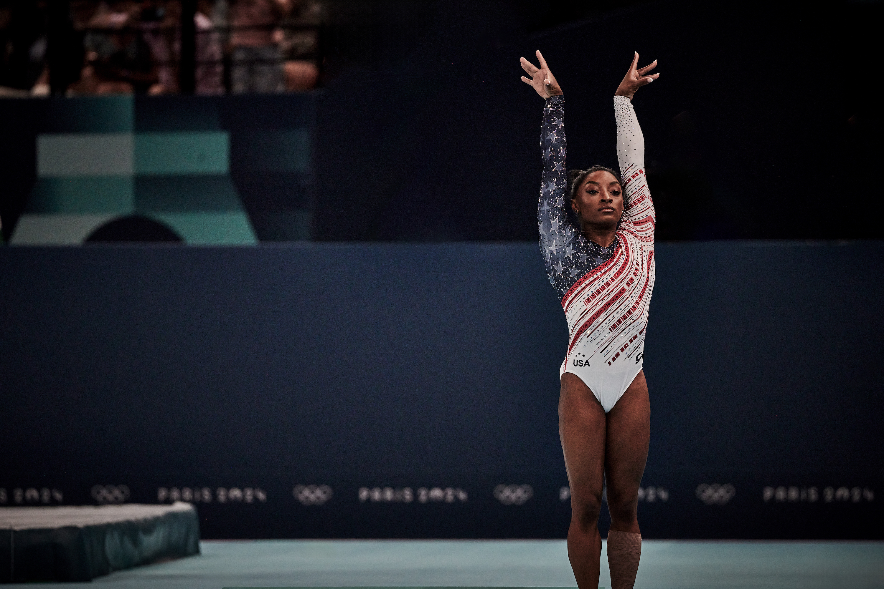 Simone Biles pose les mains en l'air lors d'une compétition.