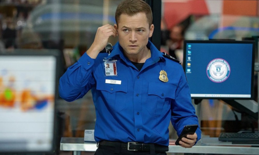 A TSA agent puts an earpiece in his ear.