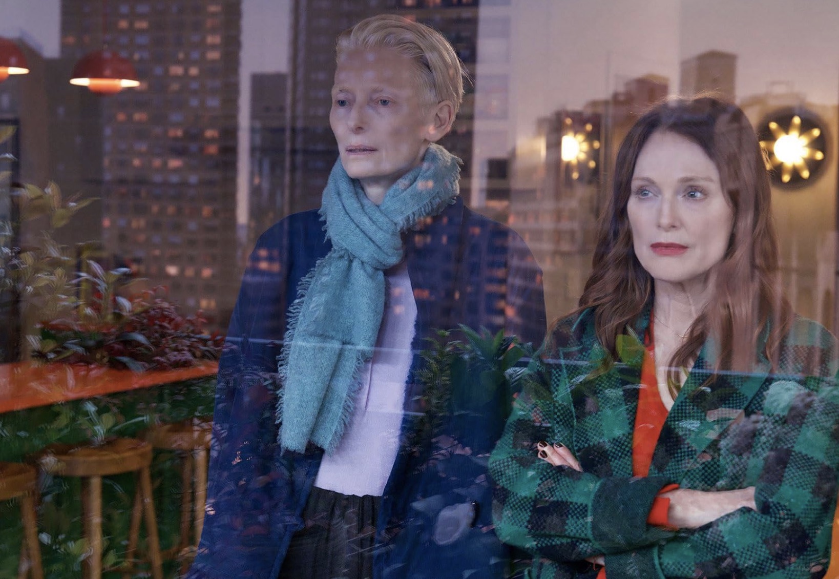 Two women stare out a window.