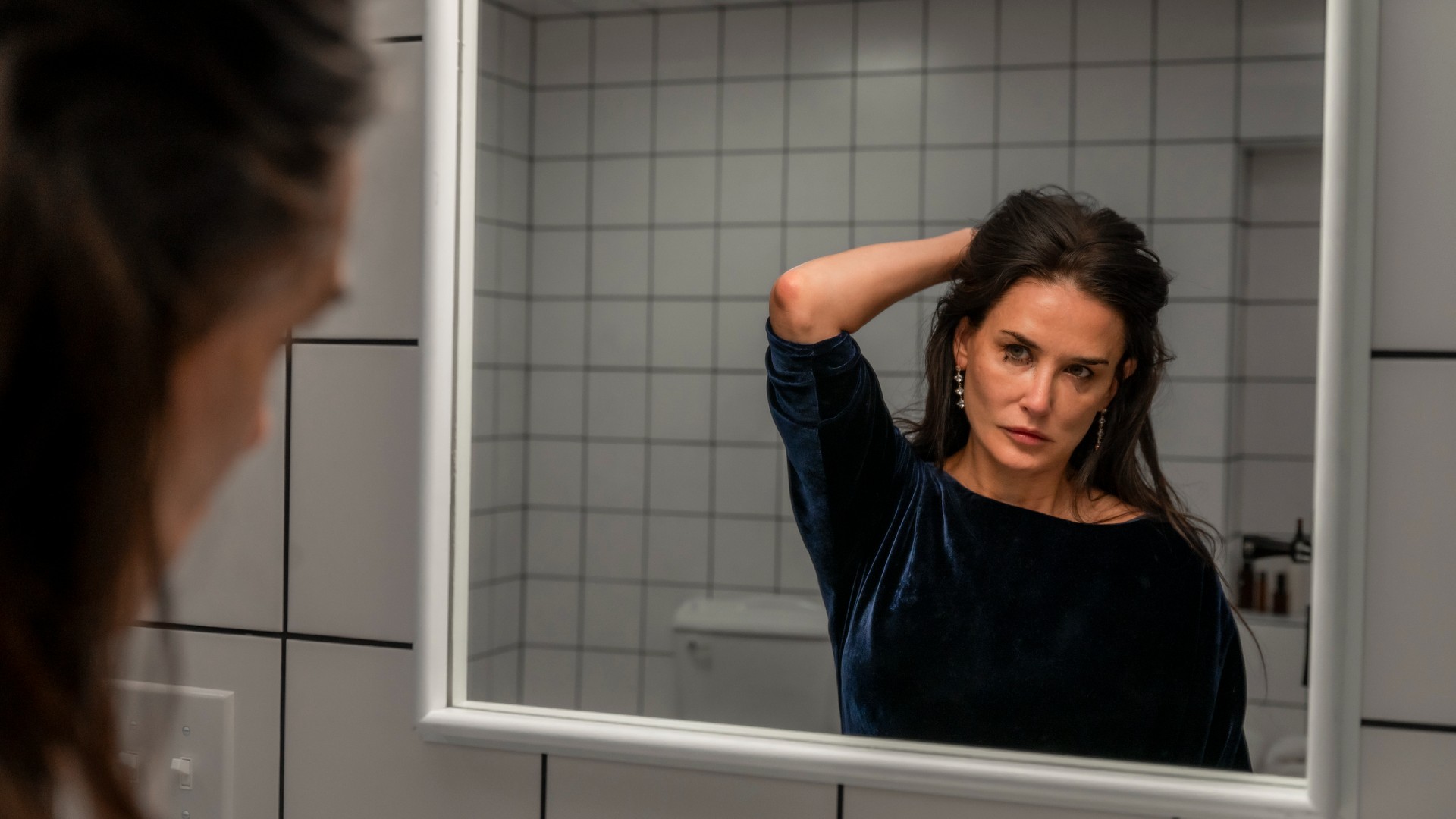 Demi Moore stares into the mirror in a still from the movie The Substance.