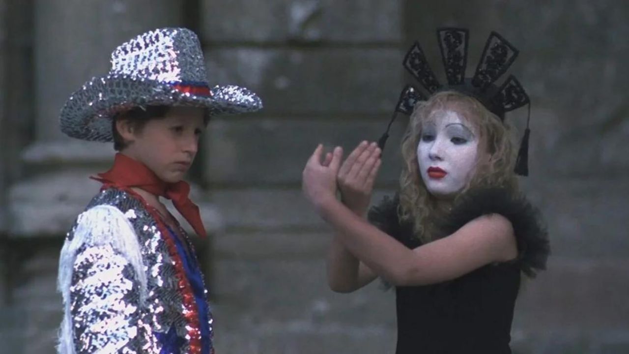 Un petit garçon en costume de cowboy regarde une petite fille maquillée en mime dans le film Santa Sangre.