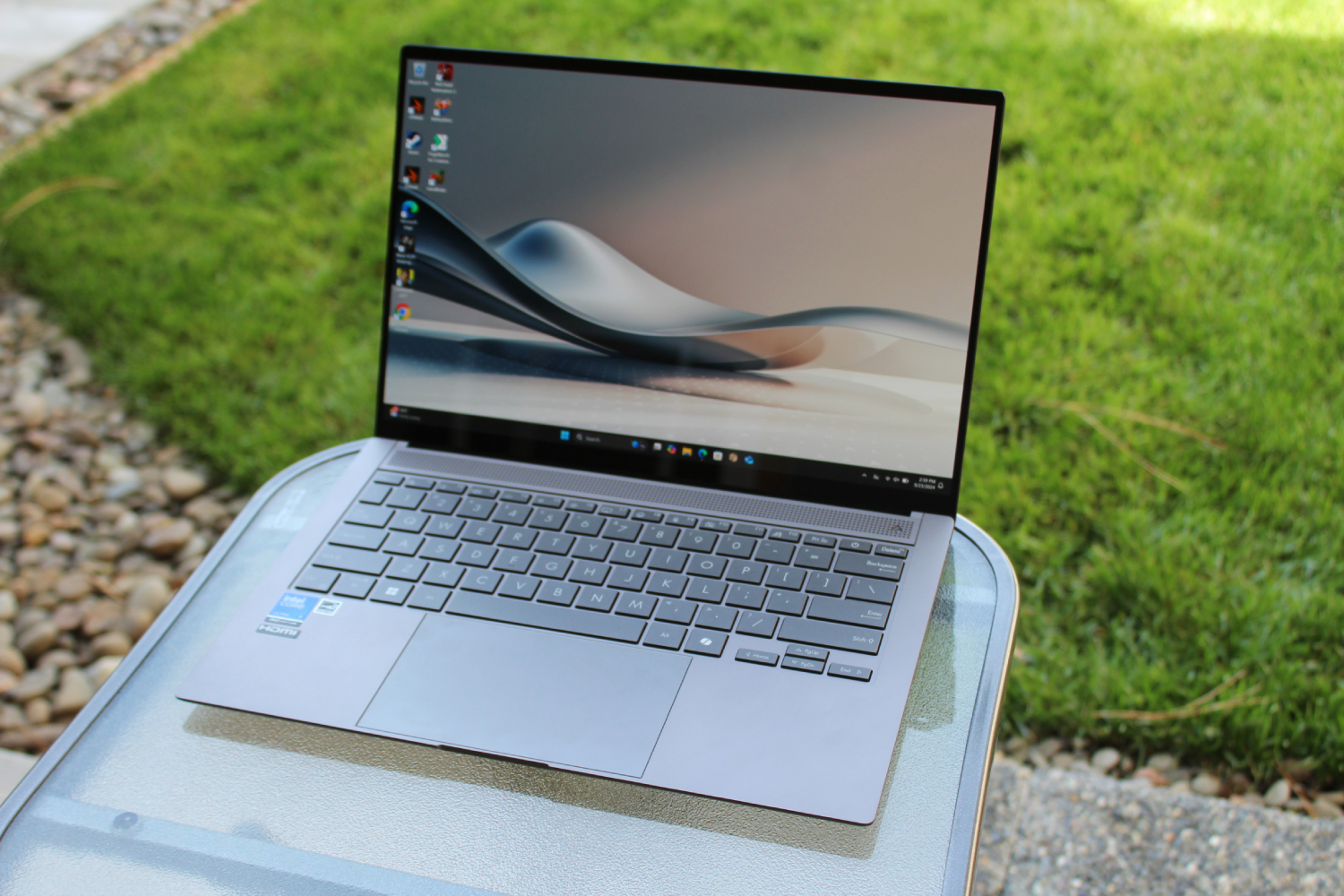 The Asus Zenbook S 14 in front of a grass lawn.