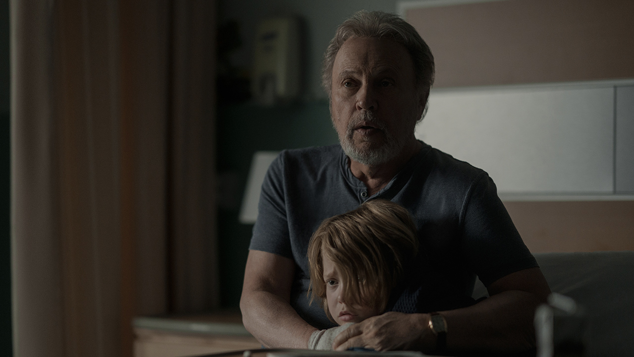 Billy Crystal abrazando y protegiendo a un niño, ambos luciendo asustados en Before en Apple TV+.