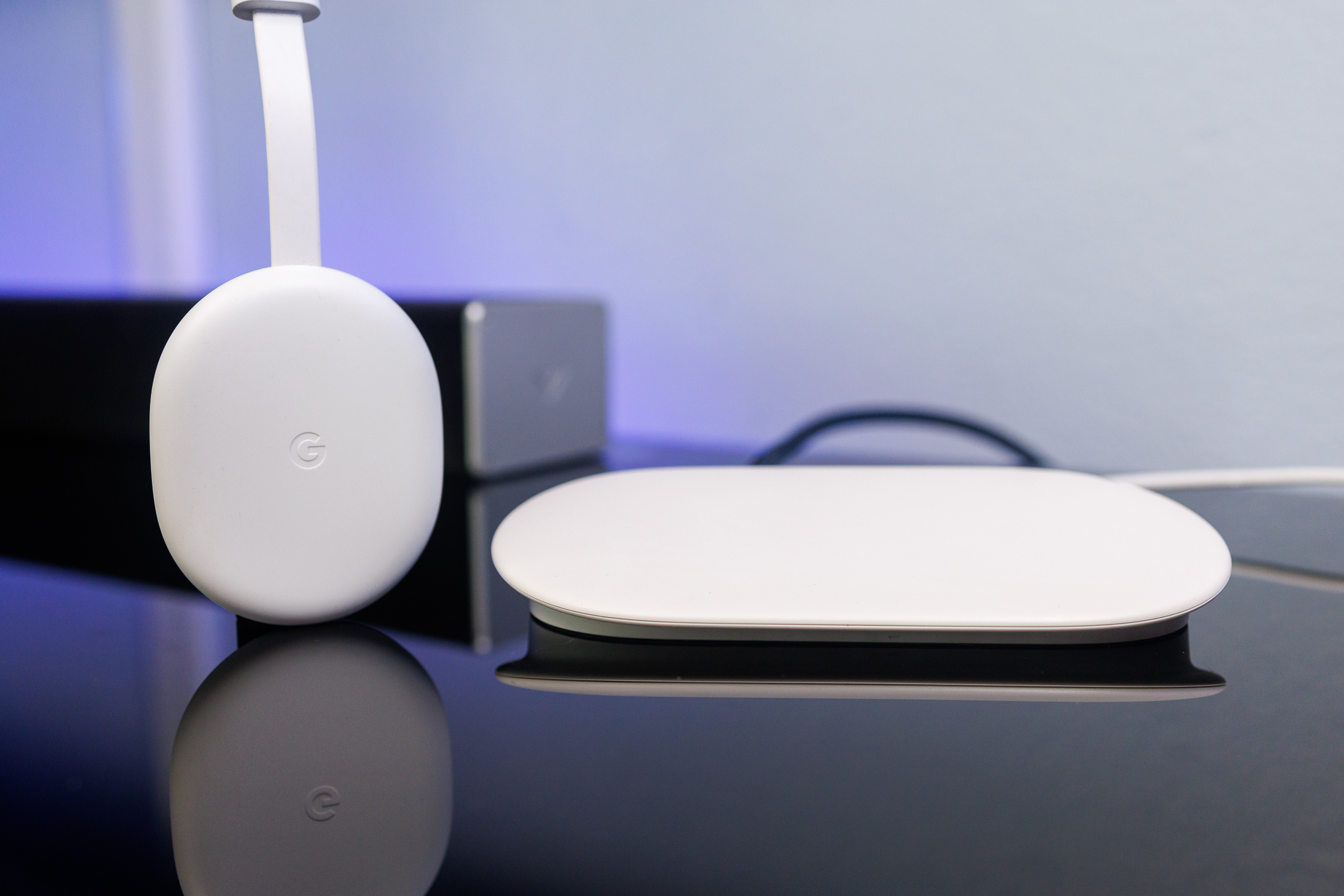 The previous-generation Chromecast standing next to the newer Google TV Streamer.