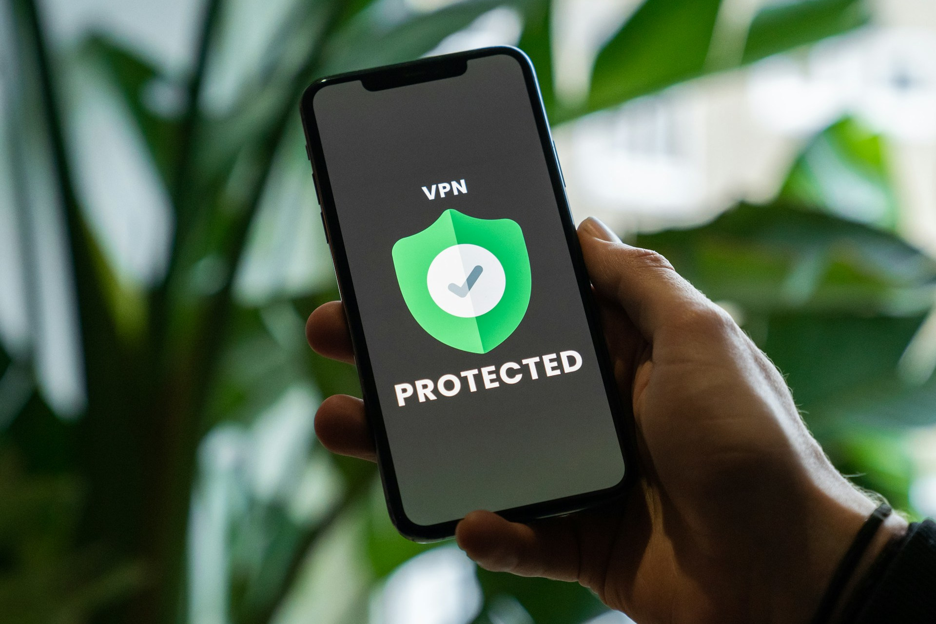 iPhone avec service VPN activé en main sur un arrière-plan flou