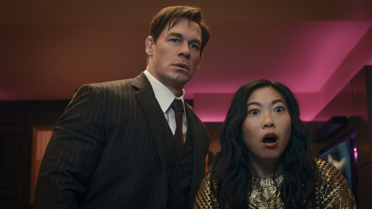 John Cena and Awkwafina look at something together, her mouth open in surprise in Jackpot!