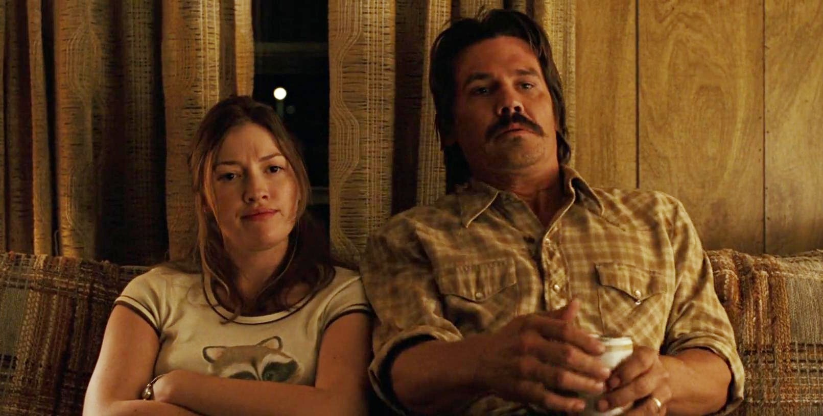 A man and a woman sit on a couch in No Country for Old Men.